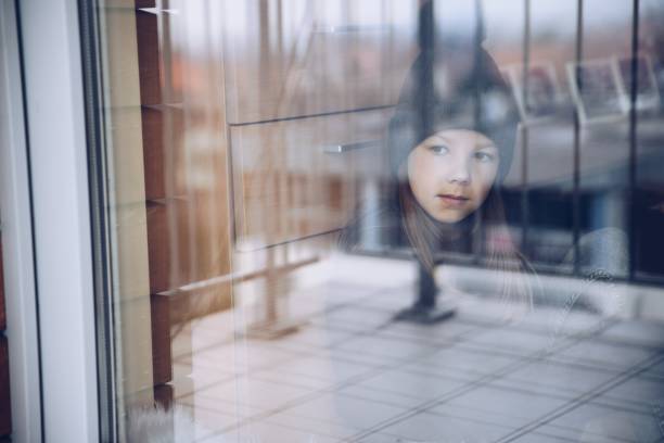 istock Melancholy and sad girl looking out the window. 1291917567