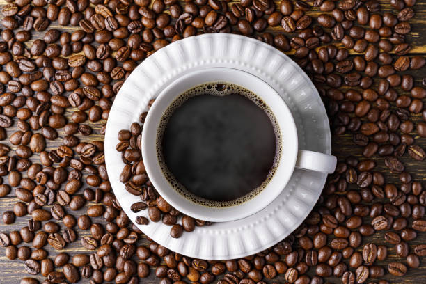 istock Hot coffee and coffee beans on wooden background 1291920927