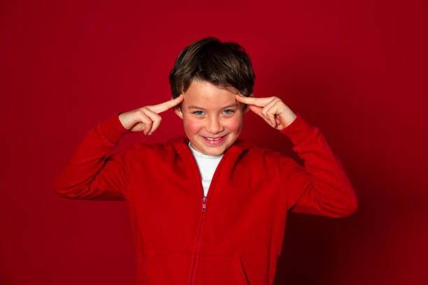 istock cool young boy posing in front of red background 1291925383