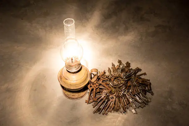 Lots of bundles of rusty keys and an old lamp in the night light.