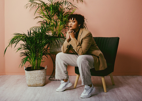 Shot of a fashionable young woman sitting on a chair in the living room