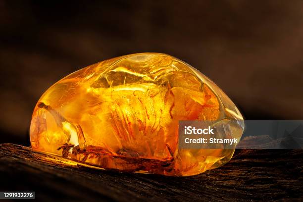 Beauty Of Natural Raw Amber A Piece Of Yellow Transparent Natural Amber On Piece Of Stoned Wood Stock Photo - Download Image Now