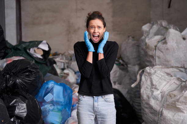 Woman screaming with hands near her face So much rubbish! Waist up portrait of shocked caucasian woman screaming with hands near her face while working at the waste recycling plant. Environmental pollution concept large dumpster stock pictures, royalty-free photos & images