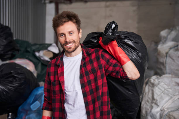 istock Man holding a heavy garbage bag over his shoulder 1291935976