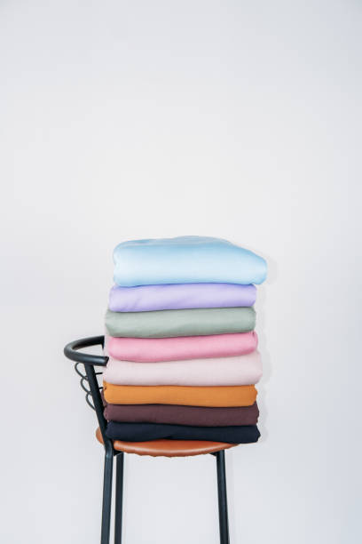 istock Stack of Pastel natural color Fabrics on white background. Fabrics And Clothing Arranged In Neat Stacks on chair. Fabrics pile background 1291936610