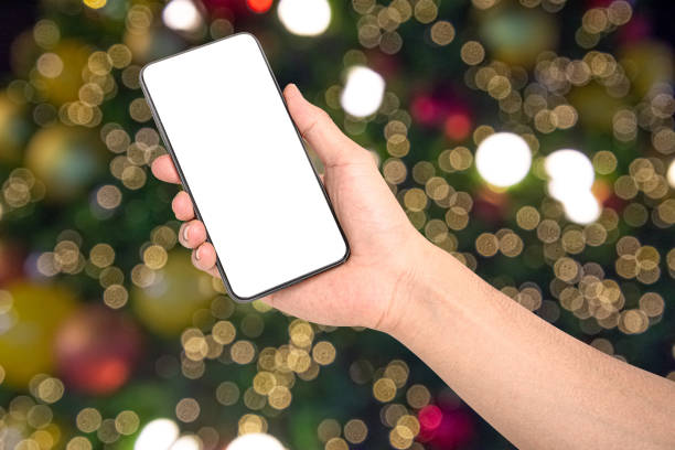 istock Close up hand holding phone isolated on white background with Illuminated  blurred bokeh of  Christmas tree decoration with  hanging lights ball. 1291936933