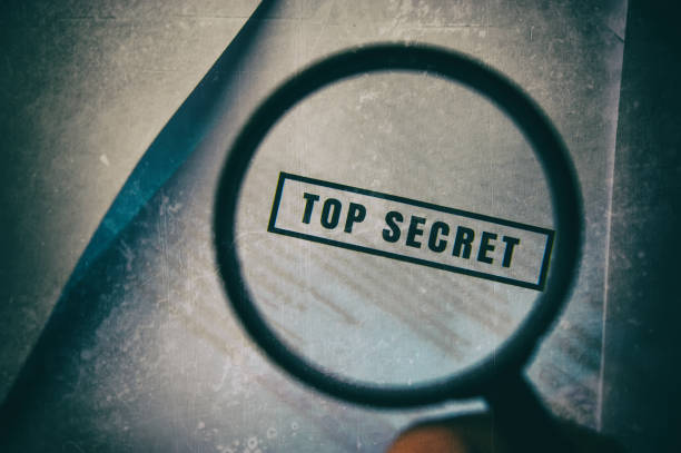 hand holds a magnifying glass over the inscription top secret - spy secrecy top secret mystery imagens e fotografias de stock