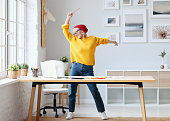 cheerful elderly woman freelancer creative designer in a red hat having fun and dancing in workplace