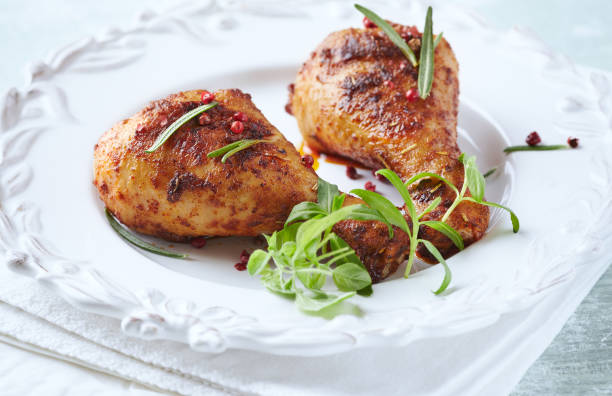 istock Baked chicken drumsticks with fresh herbs on bright background. Close up. 1291937567
