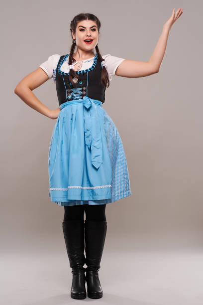 Young woman in traditional German costume on gray background