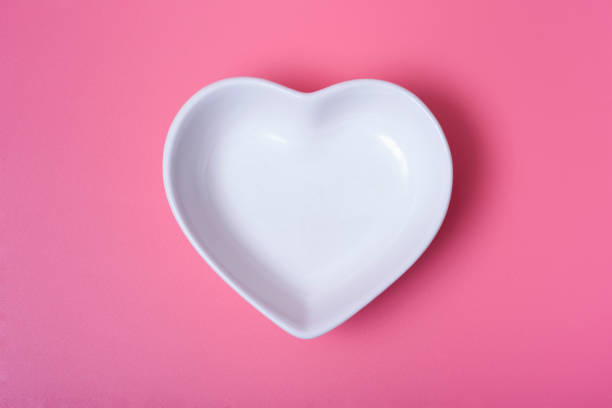 istock A heart-shaped saucer on a rose background. 1291940262