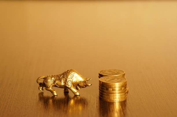 istock Metal bull with coins on a gold background. 1291940789