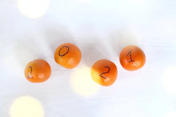 four tangerines with drawn numbers on a light table with festive illumination top view