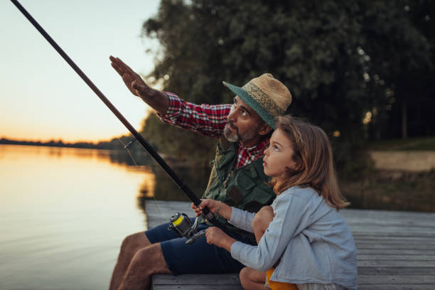 istock Grandfather teaching how to fish his granddaughter 1291944880