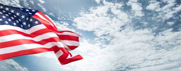 istock The American flag with a beautiful blue cloudy sky as a background. 1291947682