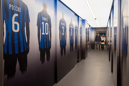 Milan, San Siro, Italy - January 22, 2019: People walk along the corridor, with drawings of football players on the walls at the Giuseppe Meazza or San Siro stadium, built in 1925.