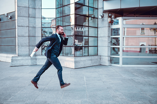 Businessman Hurrying To Catch The Bus After Work While Talking On Smartphone