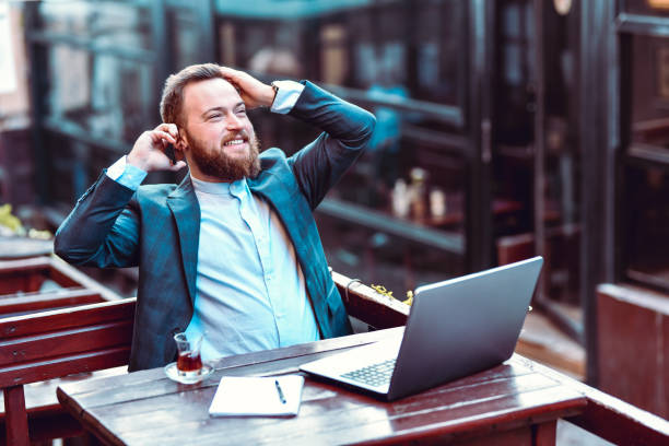 istock Businessman Talking On The Phone While Drinking Coffee And Working On Laptop 1291952760