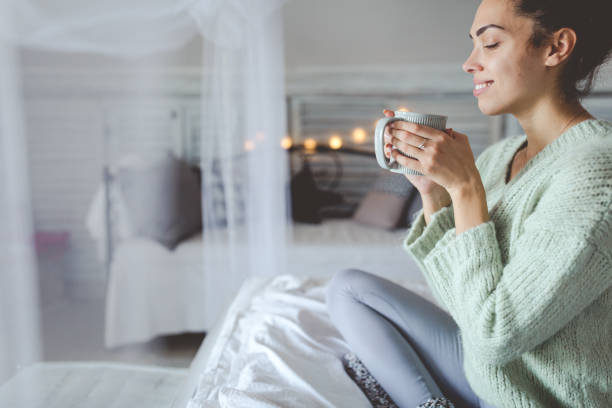 istock Beautiful young woman drinking coffee at home 1291953532