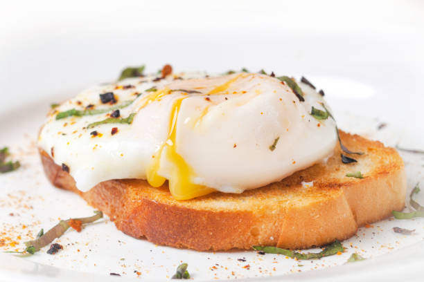 poached egg on toast with streaks of yolk on a white plate stock photo