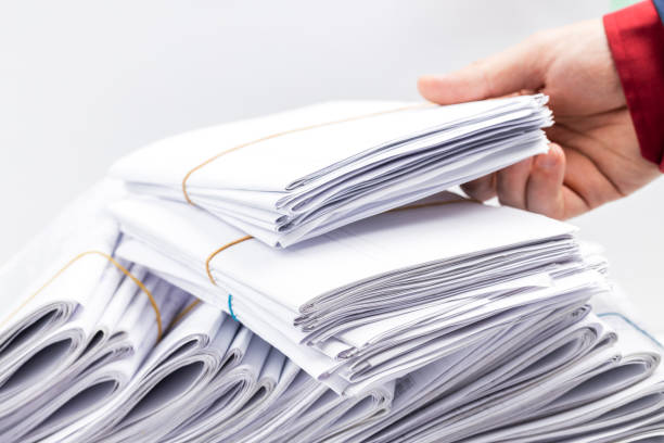 istock paperwork deadline concept. side view for a minimal workspace with big heap files. work organization conceptual. studio shot. copy space 1291955130