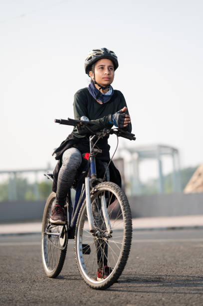 Portrait of a fit Indian female cyclist out of a training ride near Eiffel tower. She is wearing sportswear, hand gloves and helmet. Photographed in a modern contemporary style, color, vertical format with some copy space.