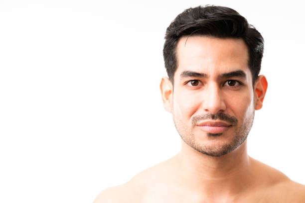 Close-up of a young man with light beard looking at camera on white background