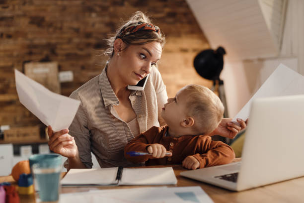 istock Multi-tasking working mother with small son at home. 1291959578