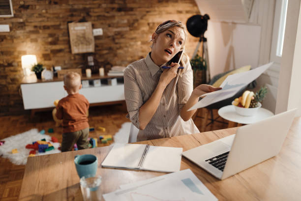 istock Distraught working mother making a phone call while going through paperwork at home. 1291959856