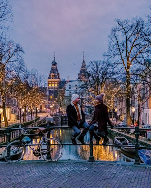 paar auf städtereise amsterdam niederlande kanäle mit weihnachtsbeleuchtung im dezember, kanal historisches zentrum von amsterdam in der nacht - amsterdam holland city night stock-fotos und bilder