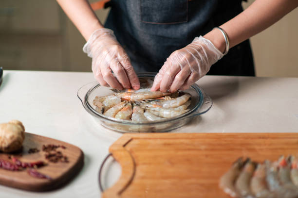 donna che ordina gamberi freschi per cucinare nella ciotola di vetro - shrimp prepared shrimp prawn prepared prawn foto e immagini stock