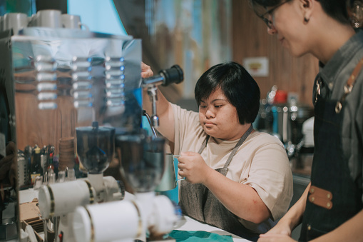 síndrome de down asiático mujer aprendiendo de barista haciendo café en su café lugar de trabajo photo