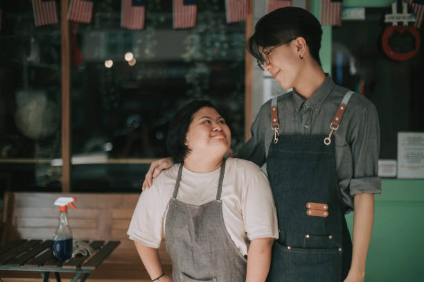 カフェの前で彼女の同僚と並んで働くアジアの女性ダウン症候群 - side by side teamwork community togetherness ストックフォトと画像