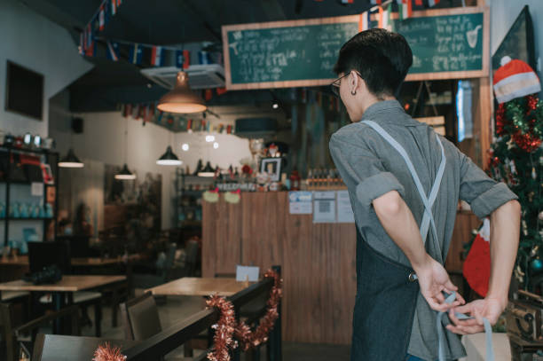 vue arrière asiatique garçon adolescent chinois serveur liant tablier se faire lire au travail à l’ouverture du café - premier emploi photos et images de collection