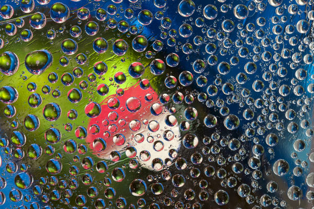 istock Multi colored drops of water are located on a blue-green background with a white-red silhouette of the heart. 1291971557
