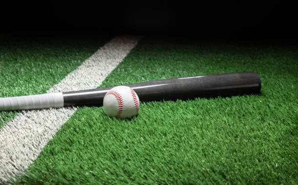 istock Baseball and gray bat on field with stripe and dark background 1291976973