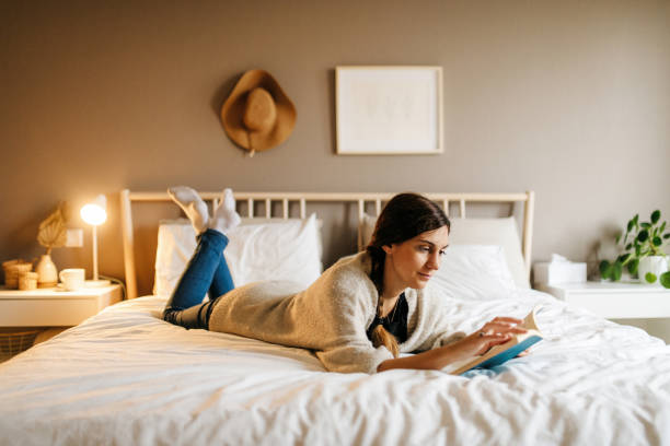 istock Woman reading a book on a bed 1291979021