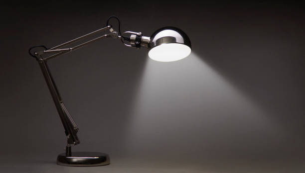 Illuminated Vintage black desk lamp isolated on black Illuminated Vintage black desk lamp isolated on black desk lamp stock pictures, royalty-free photos & images