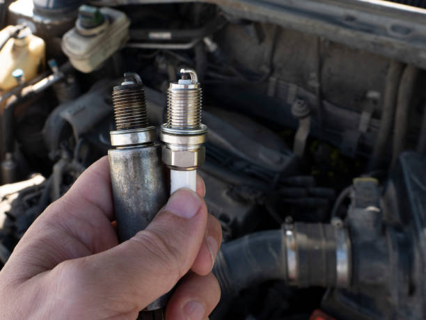 istock Man Holding old and new car spark plugs on engine background 1291979084