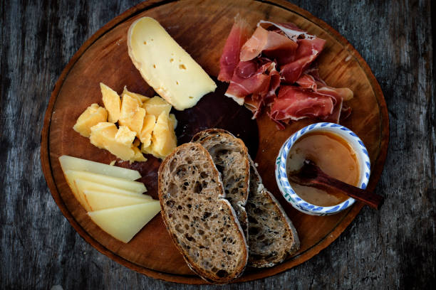 istock Round wood table with ham, cheese, bread slides, honey 1291980340