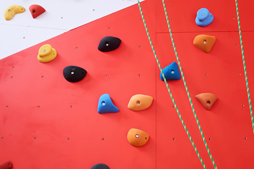 background - multi-colored climbing wall with grips and ropes