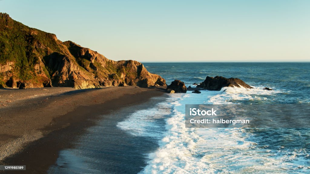 Waves Striking Beach at Shelter Cove, California - Aerial Aerial view of the black sand beach of Shelter Cove on California's Lost Coast at sunset. Northern California Stock Photo