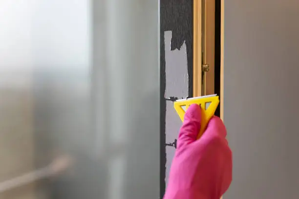 Photo of Removing protective tape from the window frame with scraper