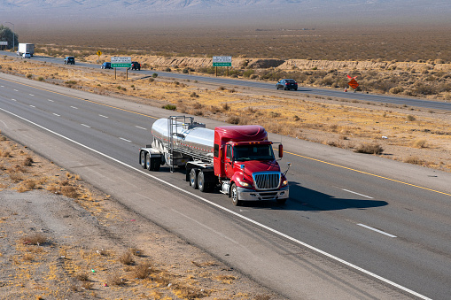 Long Haul Semi Truck on a Highway pulling an oil tank trailer.