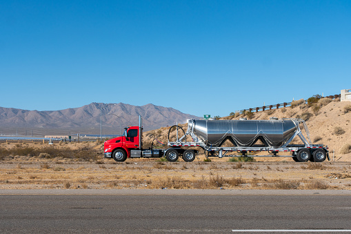 Long Haul Semi Truck on a Highway pulling an oil tank trailer.
