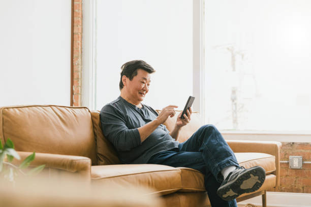 istock Sitting on sofa in apartment, silver surfer text messages friends 1291988889