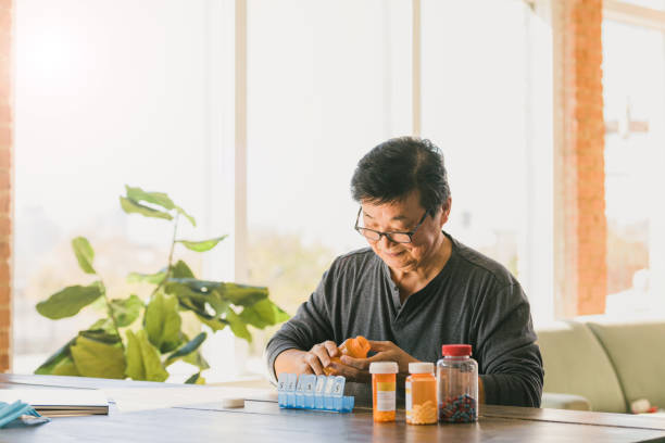 istock Widower sits at dining table to sort prescriptions into pill box 1291988923