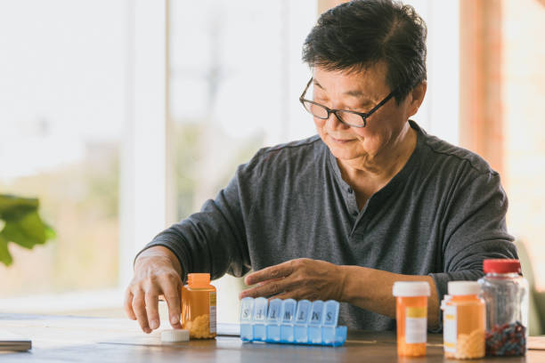 istock Senior man patiently organizes medications in pill box 1291988932