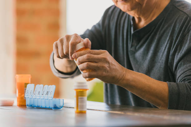 istock Unrecognizable man struggles to open prescription medication bottle 1291988948