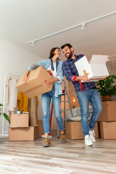 istock Couple carrying cardboard boxes with their stuff while moving in new apartment 1291991252